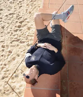 TíoCharly tumbado boca arriba en un muro junto a la playa