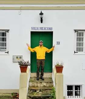 TíoCharly con los brazos abiertos en la puerta de una casa blanca